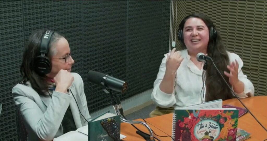 Camila Sepúlveda, ilustradora y creadora de Camil Ilustraciones, durante su entrevista en el programa Gota de Lluvia de Radio UACh, junto a la periodista Cecilia Lagos. En la imagen se observan ejemplares de sus libros infantiles ilustrados, como Tito & Benito, destacando su trabajo artesanal y creativo en Valdivia, región de Los Ríos, Chile.