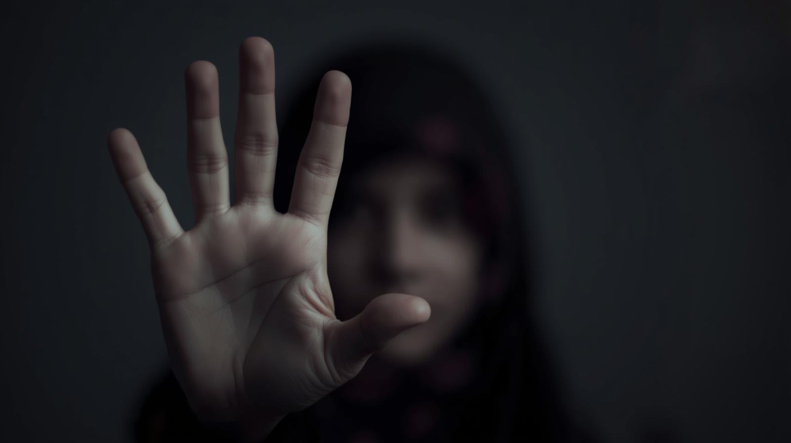 Mano en primer plano de una niña desenfocada que levanta la palma en señal de alto, imagen alusiva a la prevención de la explotación sexual infantil en la Región de Los Ríos.